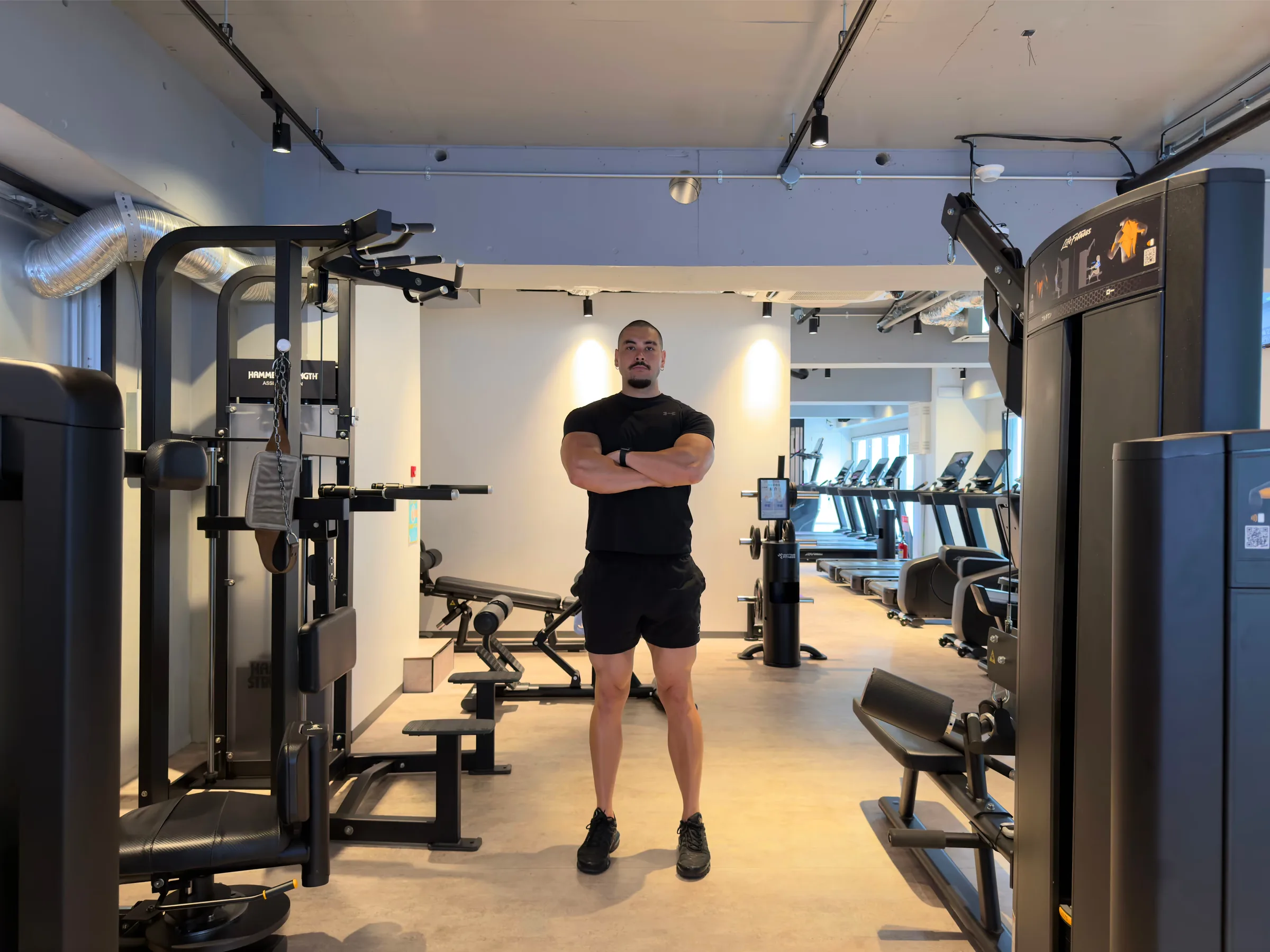 Brendan standing with his arms crossed in the middle of an empty gym in Tokyo